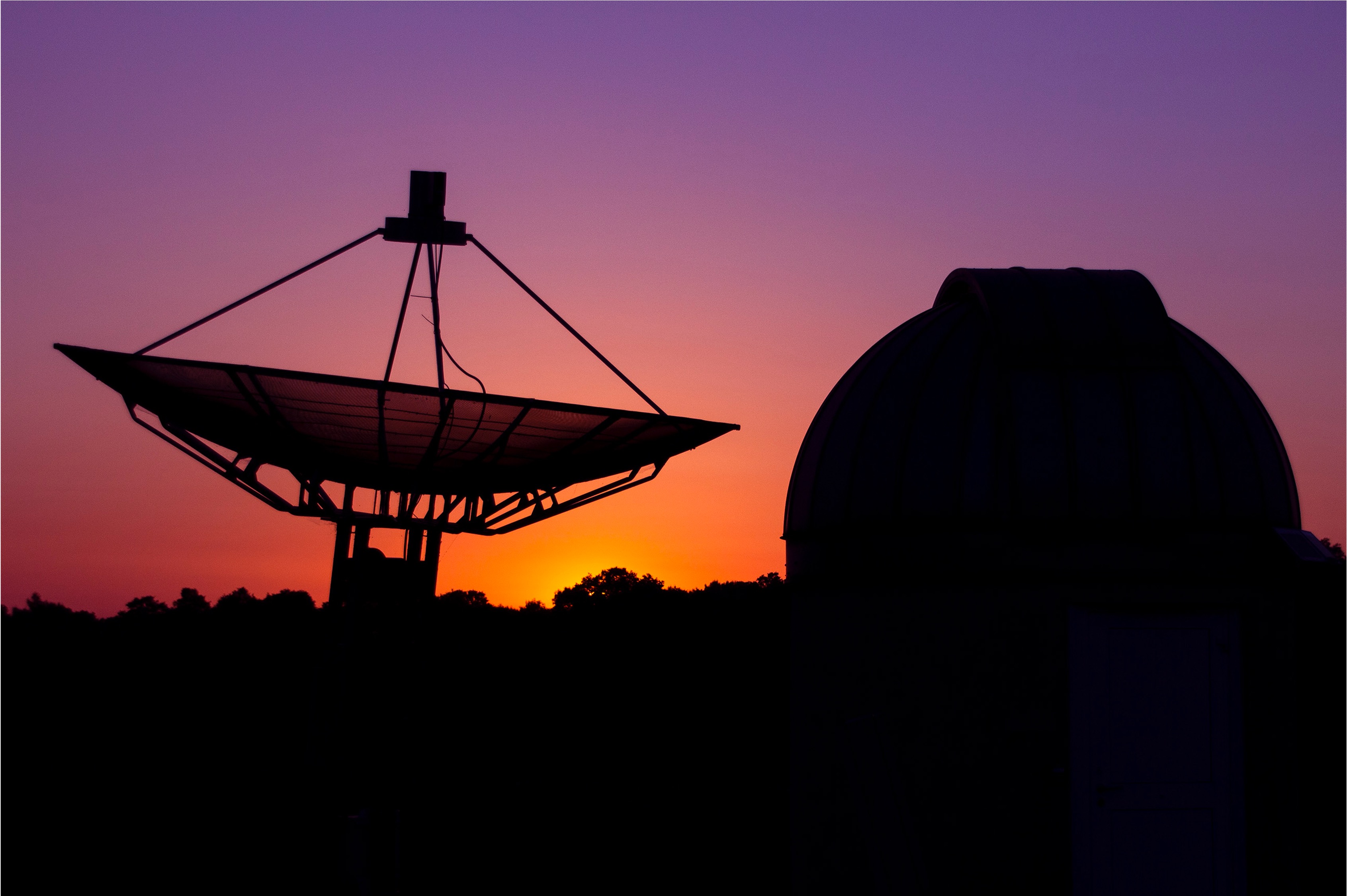 telescope dome and radio dish at sunset